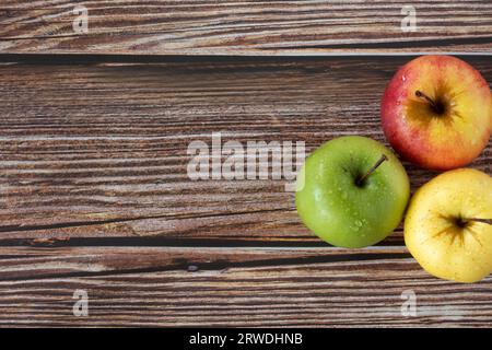 Trois pommes (rouge, verte et jaune) sur une table en bois. Vue de dessus. Espace de copie. Fruits d'automne bio frais dans différentes couleurs. Banque D'Images