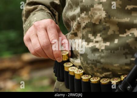 Homme prenant des cartouches de la ceinture dehors, gros plan. Saison de chasse Banque D'Images