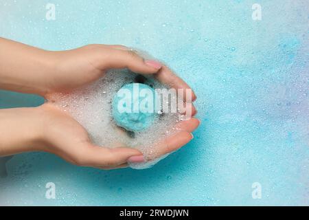 Femme tenant une bombe de bain sur l'eau avec de la mousse, vue de dessus Banque D'Images