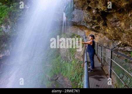 Femme derrière la cascade de Giessbach sur le flanc de la montagne en longue exposition à Brienz, Oberland bernois, canton de Berne, Suisse Banque D'Images