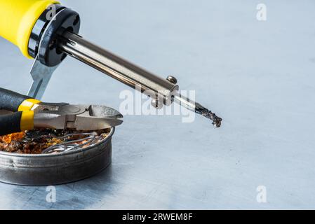 Fer à souder avec étain, colophane et pinces sur la table d'atelier Banque D'Images