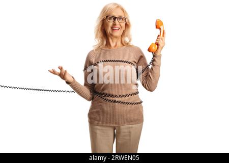 Femme mature enveloppée dans un câble tenant un téléphone rotatif isolé sur fond blanc Banque D'Images