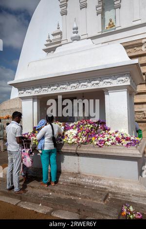 Les visiteurs du Ruvanvelisaya Dagoba à Anuradhapura au Sri Lanka déposent des fleurs dans un sanctuaire bouddhiste à la base des structures. Banque D'Images