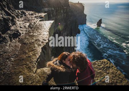 Couple de mâle et femelle plaisantant sur le bord d'une haute falaise. Homme et femme s'embrassant et aimant sur une aventure et un voyage romantique au bord de l'eau Banque D'Images