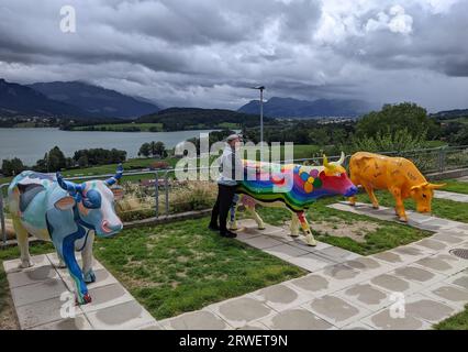 GRUYÈRE, SUISSE - 5 AOÛT 2023 : personnes posant avec des vaches peintes au Motel de la Gruyère, symbole suisse et art contemporain sur le lac landsca Banque D'Images