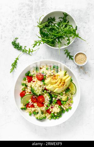 Salade de couscous avec brocoli, pois verts, tomates, avocat et roquette fraîche. Nourriture végétarienne saine à base de plantes naturelles pour le déjeuner, cuisine israélienne, Banque D'Images