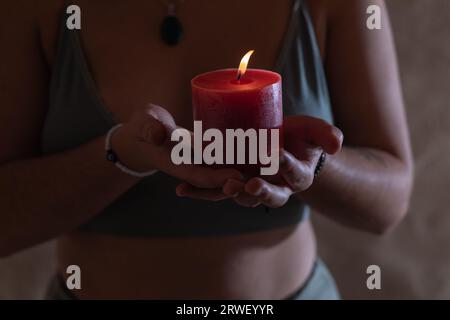 portrait rapproché des mains d'une jeune femme tenant une bougie rouge allumée Banque D'Images