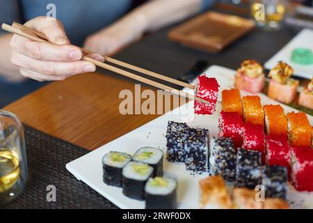 Une main de femme prend des rouleaux de poisson japonais. Banque D'Images