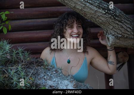 Au milieu des branches d'arbres, une jeune femme sourit joyeusement Banque D'Images