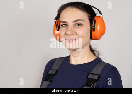 A woman wearing earmuffs and overalls on a white background. Clothing and items for builders, engineer Banque D'Images