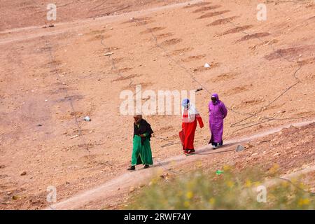 OUARZAZATE, MAROC - 18 FÉVRIER 2022 : des femmes portant des robes djellaba traditionnelles marocaines marchent sur un chemin à Ouarzazate, Maroc. Banque D'Images