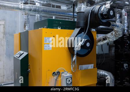 Wuppertal, Allemagne. 19 septembre 2023. Un système de chauffage à pellets peut être vu dans le sous-sol du soi-disant «règlement de protection du climat». La colonie, qui est encore en partie en construction, se compose de trois bâtiments de maisons passives avec un total de 68 appartements. Le chauffage et l'eau chaude sont fournis par des chaudières à granulés à énergie solaire thermique, un système de ventilation fonctionne avec récupération de chaleur et des systèmes photovoltaïques sont installés sur les toits. Crédit : Rolf Vennenbernd/dpa/Alamy Live News Banque D'Images