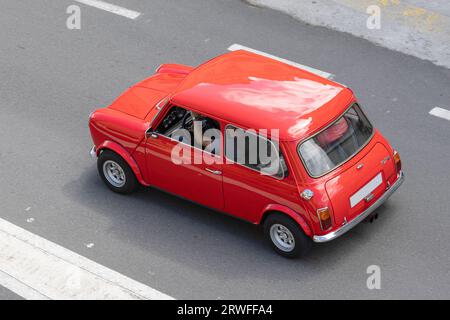 Galice, Espagne ; 27 août 2023 : vue à angle élevé d'une voiture classique Red Morris Mini conduisant sur une route Banque D'Images