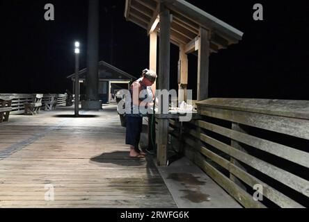 Une femme travaille sur ses prises à une station de nettoyage sur Jennette's Pier à Nags Head, Caroline du Nord. Banque D'Images