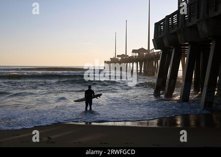 Un surfeur prend l'eau lors d'une session matinale au large de Jennette's Pier à Nags Head, en Caroline du Nord. Banque D'Images