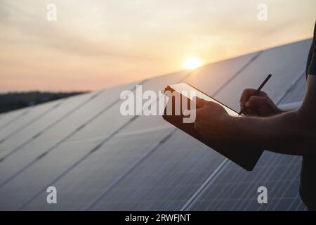 Ingénieur travaillant à l'usine de panneaux solaires en plein air - Photovoltaïque, énergie verte renouvelable et concept environnemental - Focus main gauche Banque D'Images
