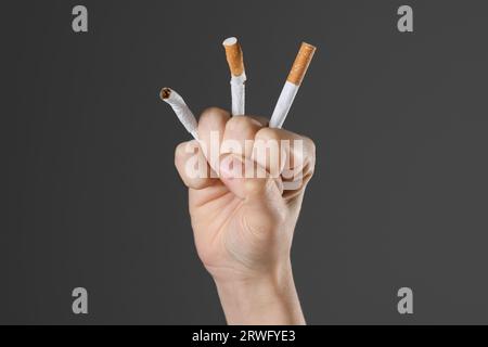 Concept d'arrêt de fumer. Femme écrasant des cigarettes sur fond gris, gros plan Banque D'Images