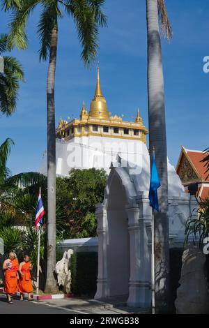 Deux moines bouddhistes marchant dans les vastes jardins de Wat Saket, Bangkok, Thaïlande, avec l'emblématique Mont d'Or (Phukhao Thong) en arrière-plan Banque D'Images