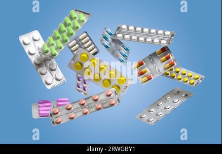 Beaucoup de pilules et de capsules de médecine colorées dans des blisters volant sur fond bleu Banque D'Images