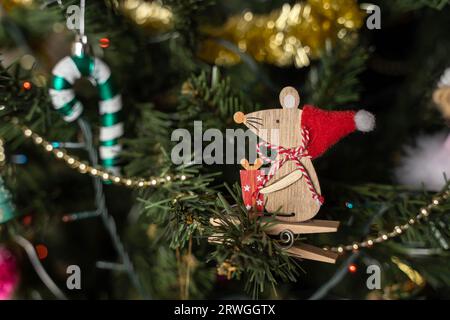 Jouets miniatures d'arbre de Noël sur les branches d'un arbre de Noël. Une souris en bois dans un chapeau de Père Noël et une canne au caramel. Le concept de célébrer le Christ Banque D'Images