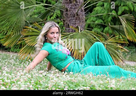 Femme blonde aux cheveux longs et tenue verte posant dans la nature Banque D'Images