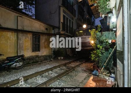 Un train traverse Hanoi train Street, Hanoi, Vietnam, dans la soirée. Banque D'Images