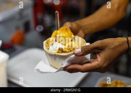 Main tenant la crème glacée à la noix de coco et à la mangue dans la coquille de noix de coco au marché de rue Jalan Alor à Kuala Lumpur Banque D'Images