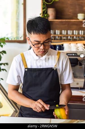 Chef vietnamien épluchant la mangue fraîche dans un café Banque D'Images