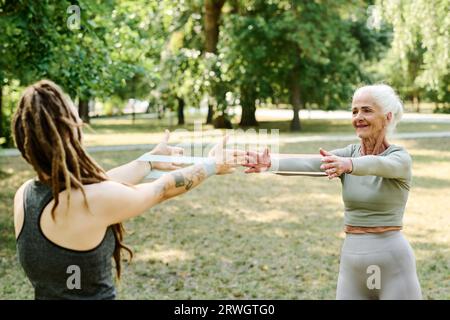 Femme âgée ayant une formation privée avec entraîneur, ils font des exercices avec de l'élastique Banque D'Images