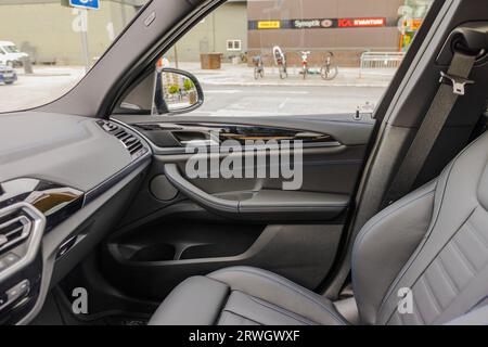 Belle vue de l'intérieur de la voiture en cuir BMW iX3 M-sport avec siège avant passager garé dans le parking près du centre commercial. Banque D'Images