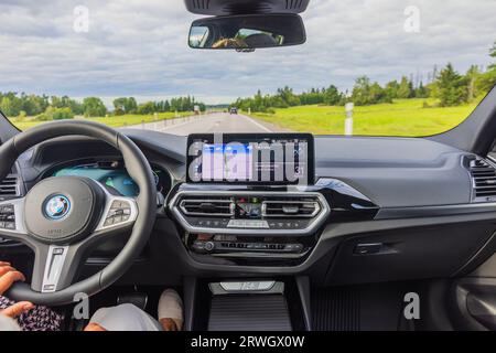 Vue de la femme conducteur conduisant le nouveau modèle électrique de voiture de sport BMW iX3 M sur l'autoroute. Banque D'Images