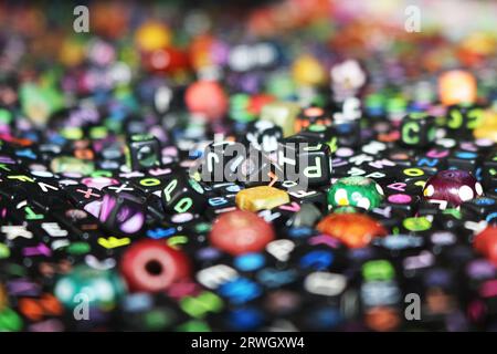 image abstraite de dés/cubes en plastique de couleur noire sur des lettres de l'alphabet Banque D'Images