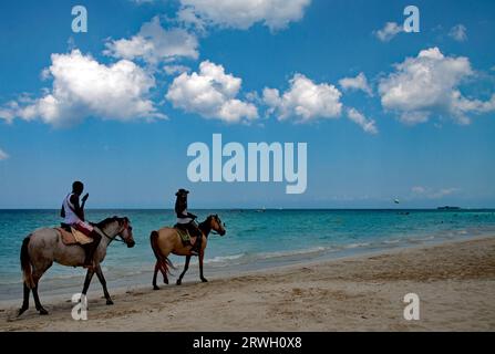 Deux jeunes hommes à cheval sur la Seven Mile Beach à Negril en Jamaïque Banque D'Images