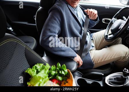 Gros plan d'un homme âgé méconnaissable attachant la ceinture de sécurité dans la voiture, espace de copie Banque D'Images