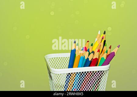 Crayons de couleur dans une boîte blanche sur fond vert Banque D'Images