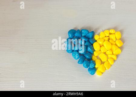 Coeur bleu et jaune sur fond blanc avec espace de copie. Pierres bleues et jaunes. Couleurs nationales ukrainiennes. Figurine en forme de coeur. Concept patriotisme. Banque D'Images