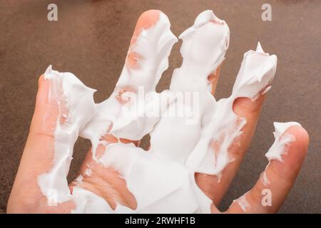 Mousse à raser sur une main sur un fond sombre Banque D'Images