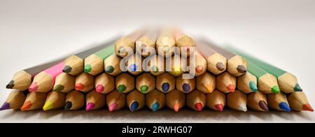 Une sélection de crayons de couleur soigneusement placés en formation sur une surface blanche sous éclairage studio. Banque D'Images