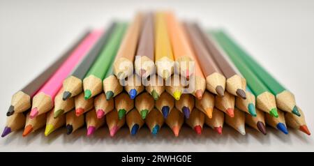 Une sélection de crayons de couleur soigneusement placés en formation sur une surface blanche sous éclairage studio. Banque D'Images