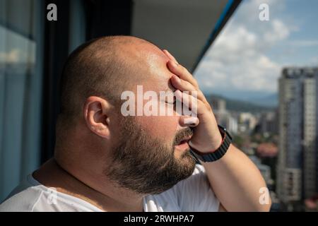 Portrait de l'homme en surpoids a mal à la tête touchant le front dans la chaleur temps d'été. Banque D'Images