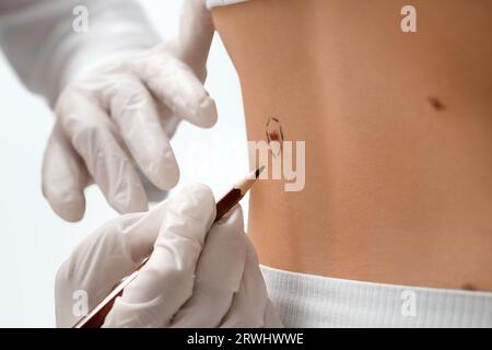 Dermatologue marquant la taupe de jeune femme sur fond clair, gros plan Banque D'Images