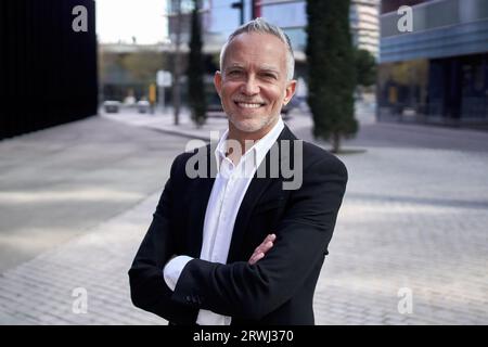Photo souriant homme d'affaires mature regardant la caméra bras debout croisés à l'extérieur de l'immeuble de bureaux. Banque D'Images