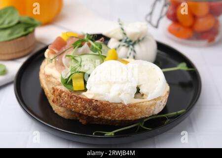 Savoureux sandwich avec fromage burrata, prosciutto et légumes sur table blanche, gros plan Banque D'Images