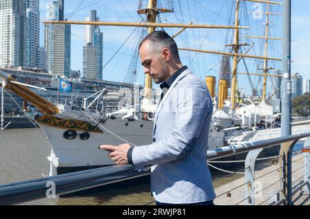 Homme d'affaires adulte français caucasien, portant une veste intelligente, debout à l'extérieur vérifier le téléphone, lire des messages et regarder les médias sociaux et e-mail Noti Banque D'Images