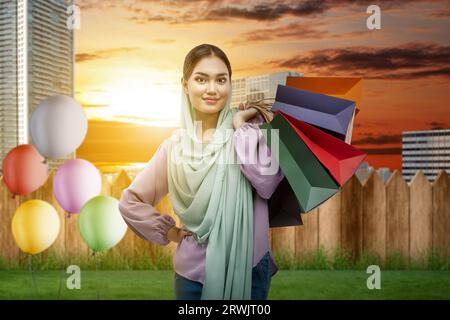 Une femme asiatique en voile présente un sac à provisions tout en célébrant une fête d’anniversaire. Concept de femme Joyeux anniversaire Banque D'Images