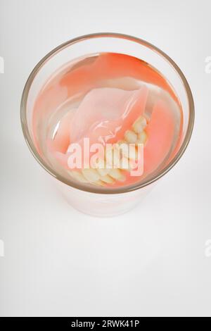 Vieux dentier dans un verre d'eau Banque D'Images