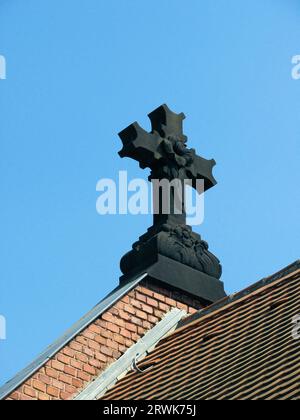 Croix de pierre sombre sur le toit d'une chapelle à Sulzbach Saar, fond de ciel bleu Banque D'Images