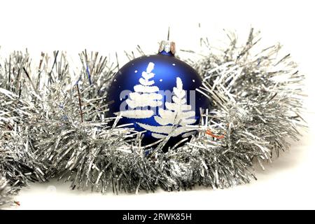 Boule bleue avec arbre de noël sur scintillant argenté isolé sur blanc Banque D'Images