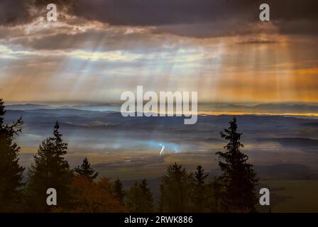 Rayons de lumière divine passant à travers les nuages au petit matin au-dessus de campagne vallonnée Banque D'Images
