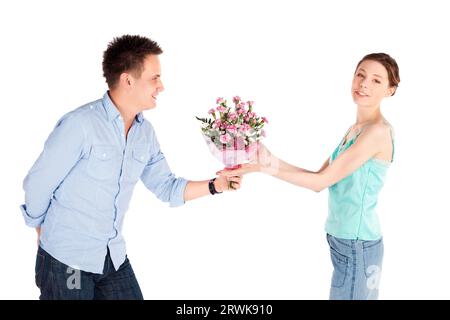 Cheerful casual couple heureux isolé sur blanc, homme romantique donnant des fleurs pour sa petite amie Banque D'Images